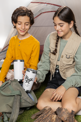 two young girls sitting on the ground next to a tent