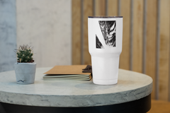 a white cup sitting on top of a table next to a plant