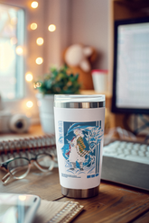 a coffee cup sitting on a desk next to a computer